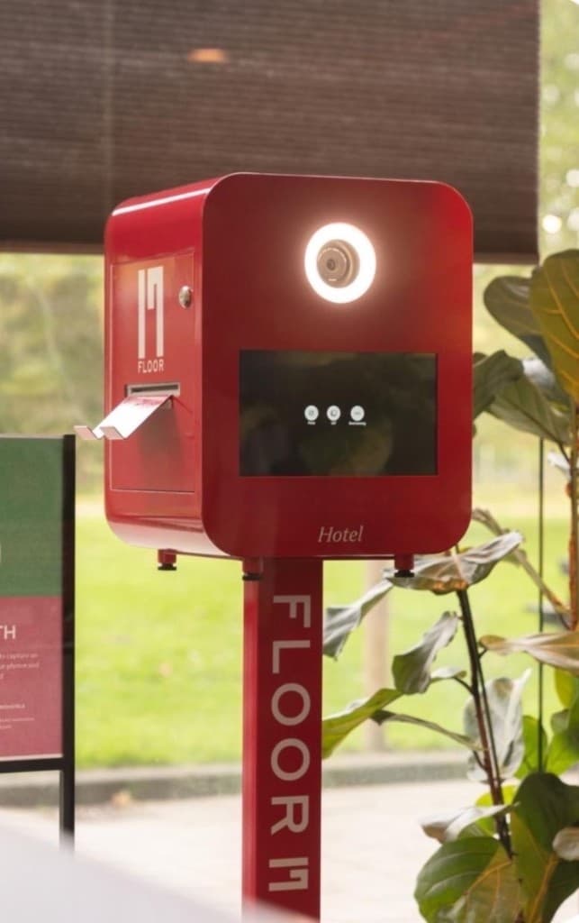 Gepersonaliseerd fotopaaltje met merklogo op de vloer en donkere cabine.